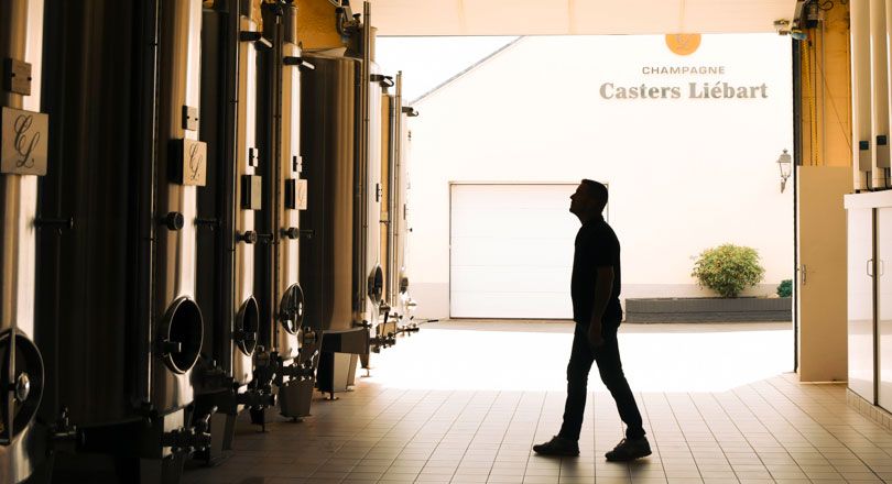 Mann in einer Halle , vor Metallweintanks , im Hintergrund ist das Gebäude von Casters Liebert 